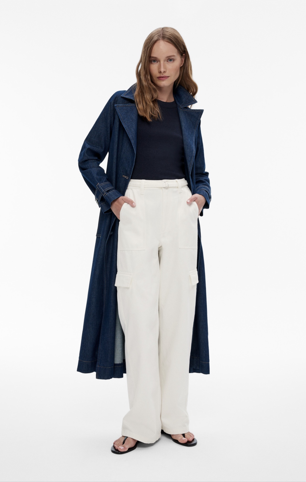 Woman in denim trench coat, black tank top, white cargo pants, white leather belt and black leather sandals