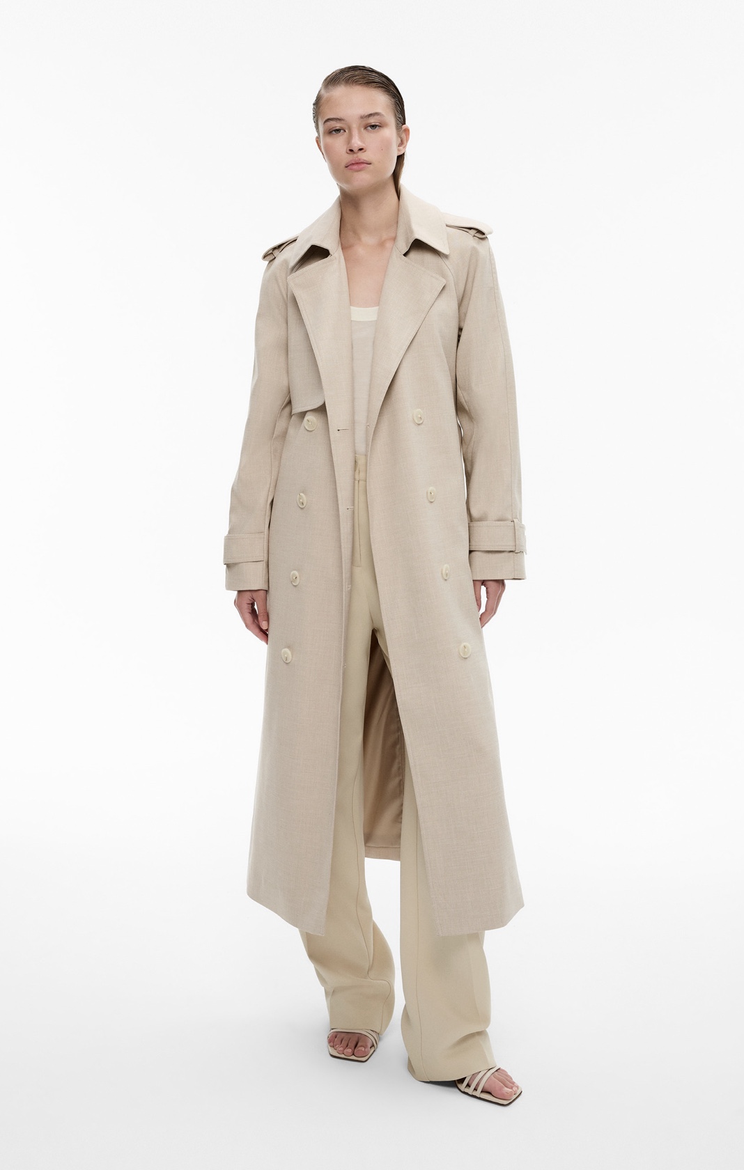 Woman in beige trench coat, cream knit tank and beige pants