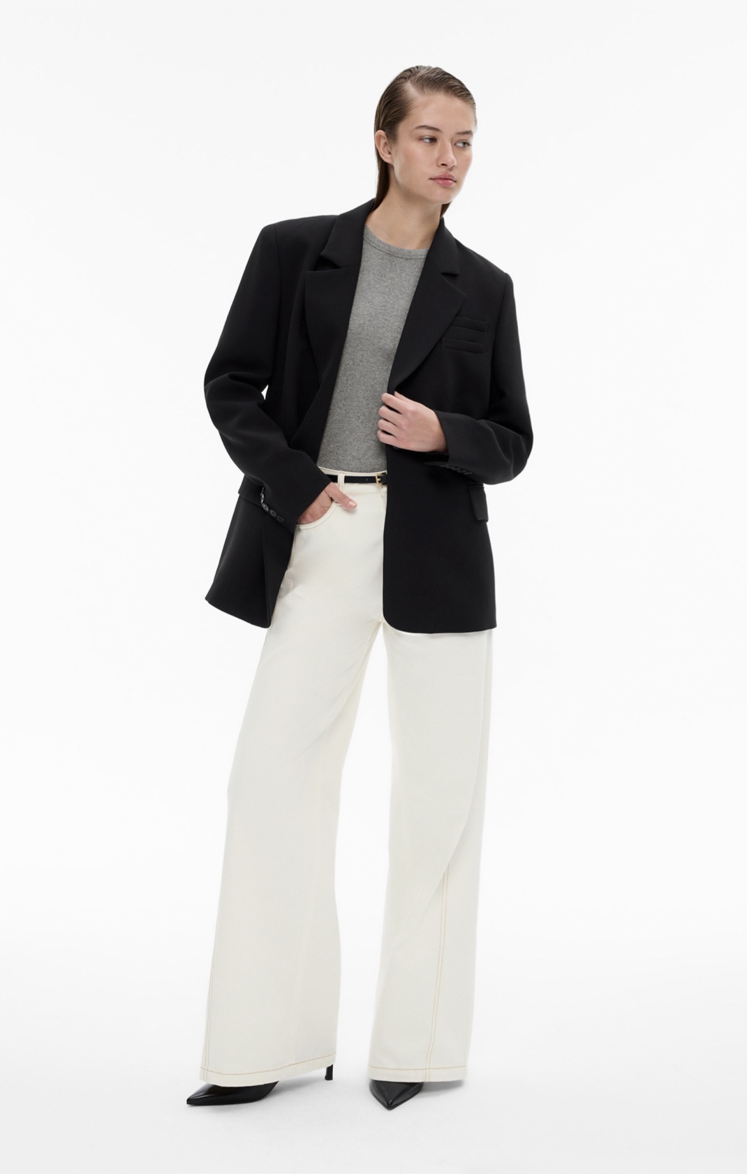 Woman in black blazer, grey knit tank, white denim jeans, black leather belt and black point heels