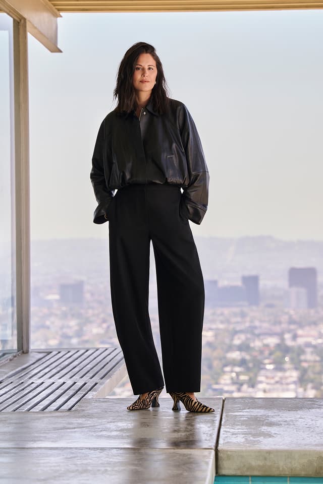 Dani Michelle wearing a black shirt and tailored trousers overlooking the city